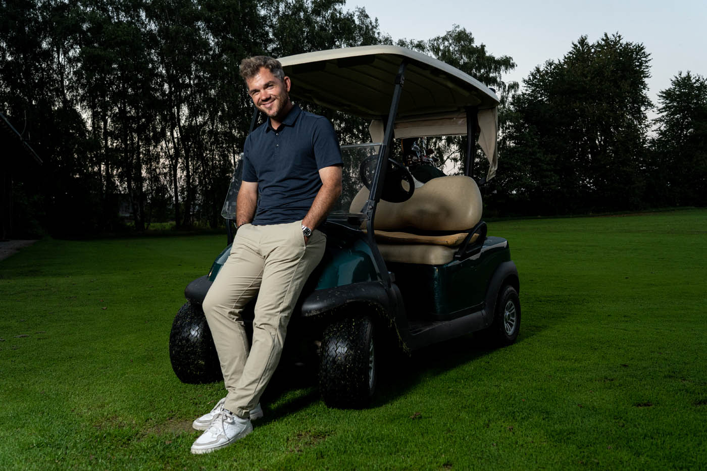 Benjamin Wuttke steht an einem Golf Caddy